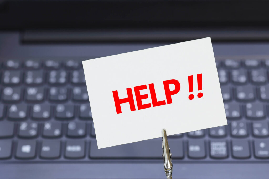 パソコンのキーボードと「HELP!」と書かれたメモ