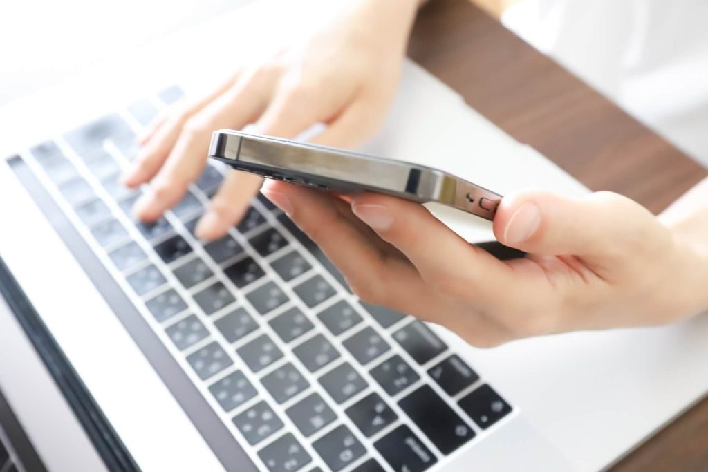 スマホを見ながらパソコンを操作しているイメージ画像01